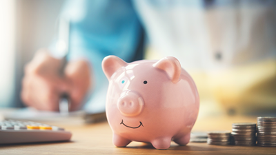 Pink piggy bank with person behind calculating money