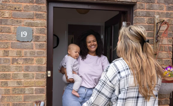Mum and baby chatting with friend at front door