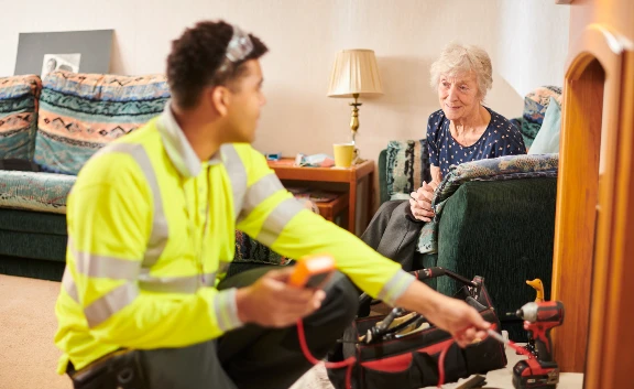 Repairs operative fixing something in lounge with older lady