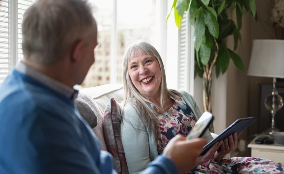 Older couple sat on sofa laughing together