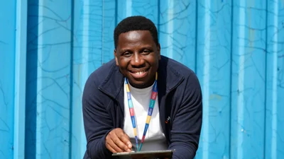 A Moat colleague sits holding a tablet in front of a blue background 