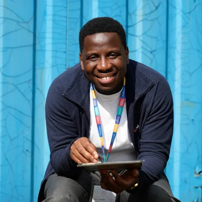A Moat colleague sits holding a tablet in front of a blue background 