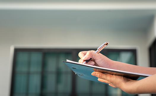 Person with clipboard and pen outside a house