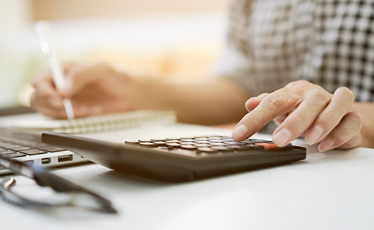 Person with laptop, pen and paper and calculator