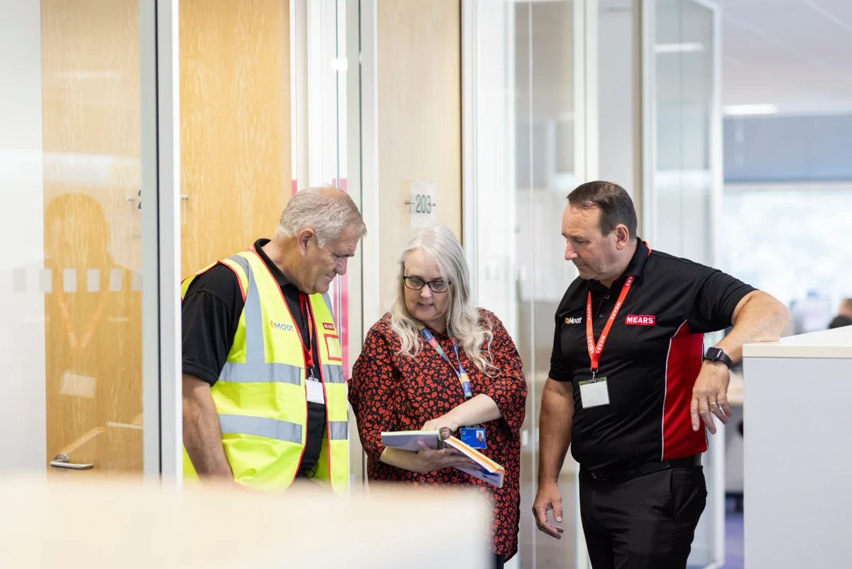 Moat and Mears colleagues stand together looking at notebook