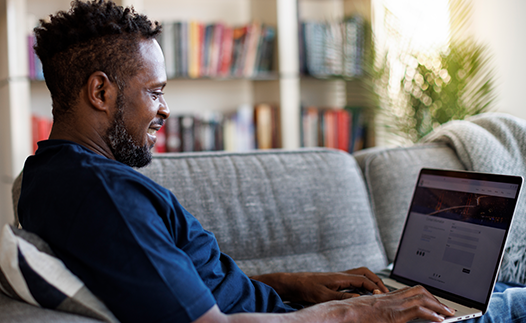 Man sat on sofa with laptop open on his lap