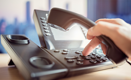 Person dialling a number on desk phone