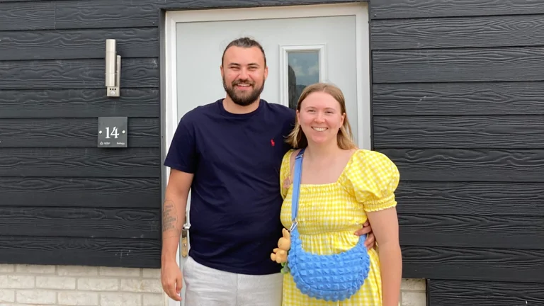 Couple stand outside their new home