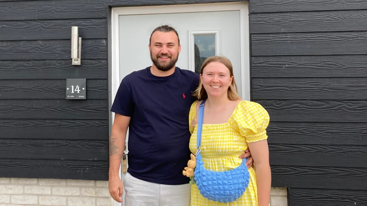 Couple stand outside their new home