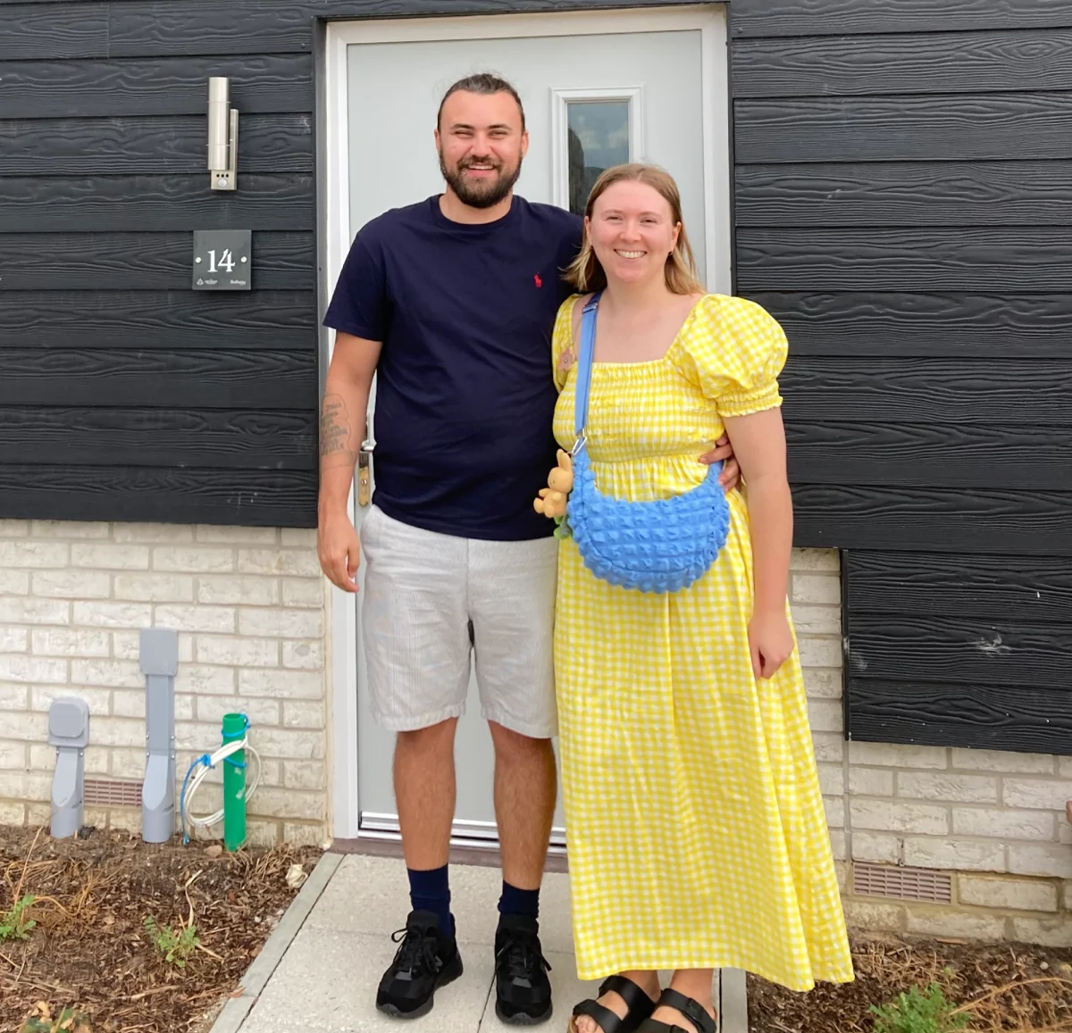 Couple stand outside their new home