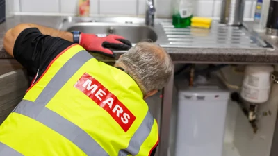 Mears operative fixing something under a kitchen sink