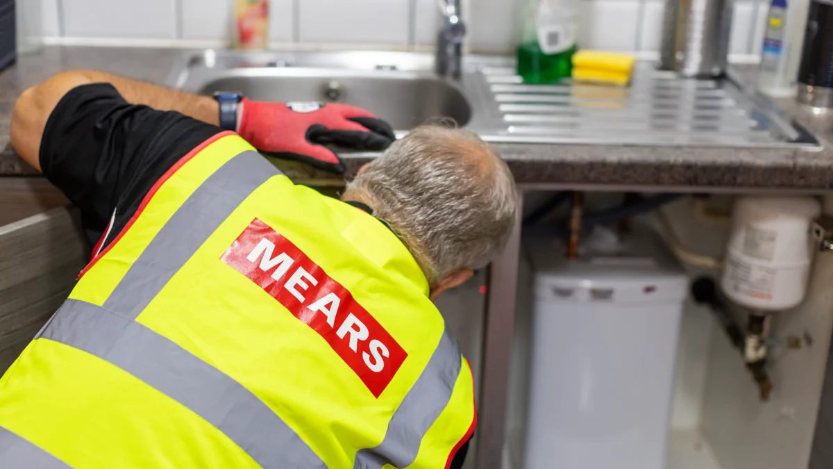 Mears operative fixing something under a kitchen sink